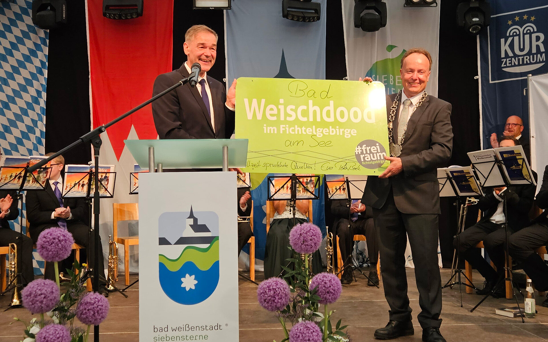 Übergabe eines persönlich signierten und modifizierten Mundart-Ortschildes „Bad Weischdood am See“ aus einer Freiraum für Macher-Kampagne durch Landrat Peter Berek an den Bürgermeister Matthias Beck.